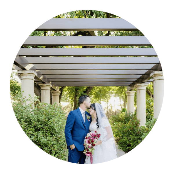 A bride and groom standing under a pergola.