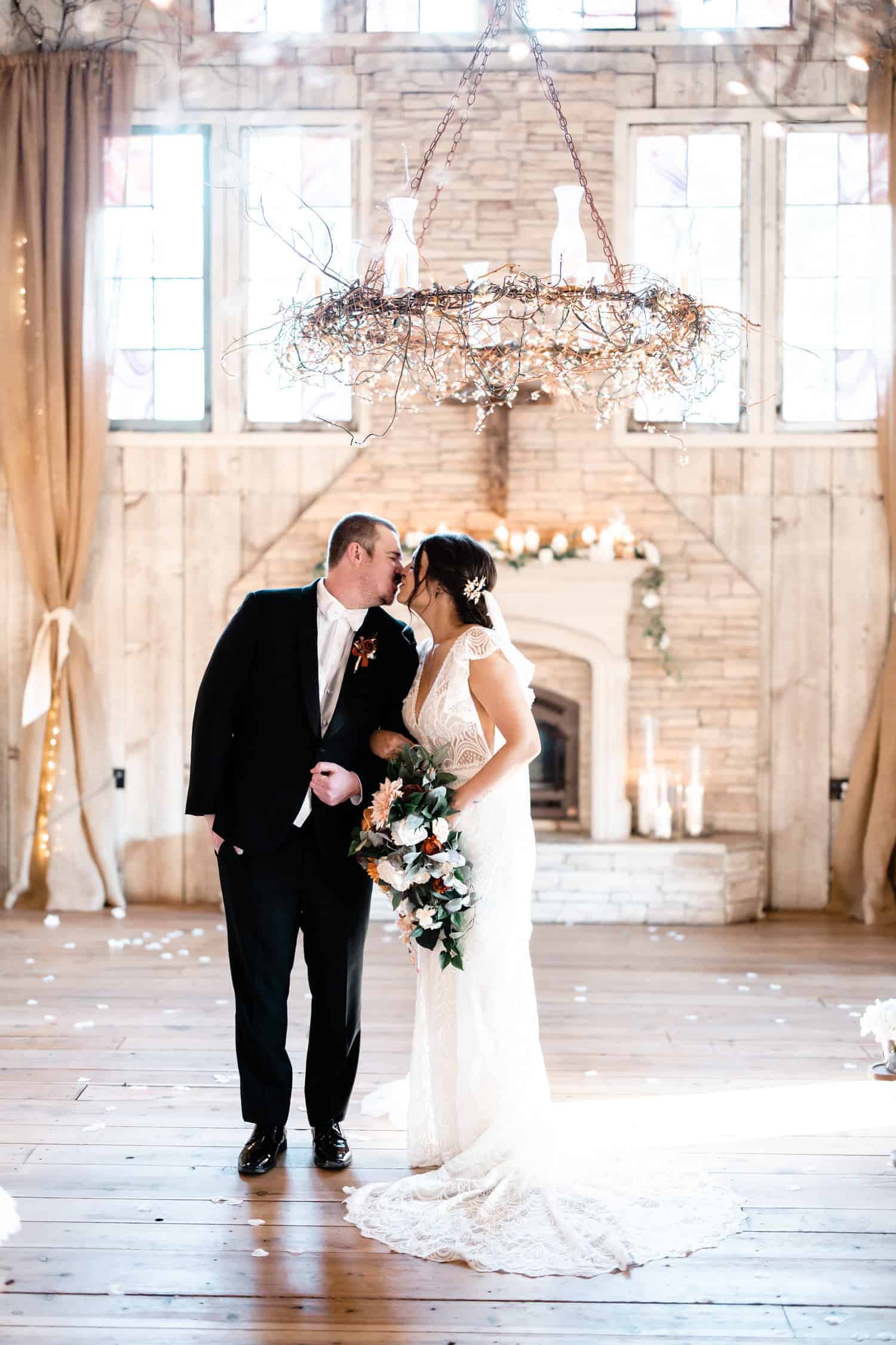 A bride and groom kissing in front of a chandelier.